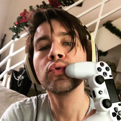 He is wearing a headphone while the controller is white themed dual shock 4.